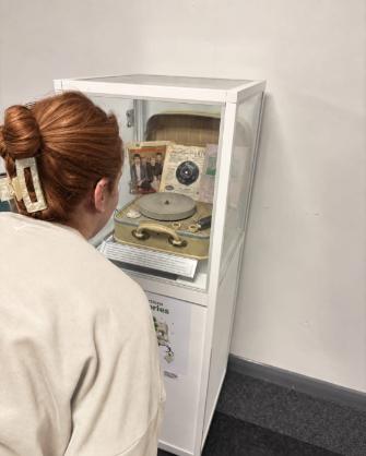 Lady peering into museum box with a record player